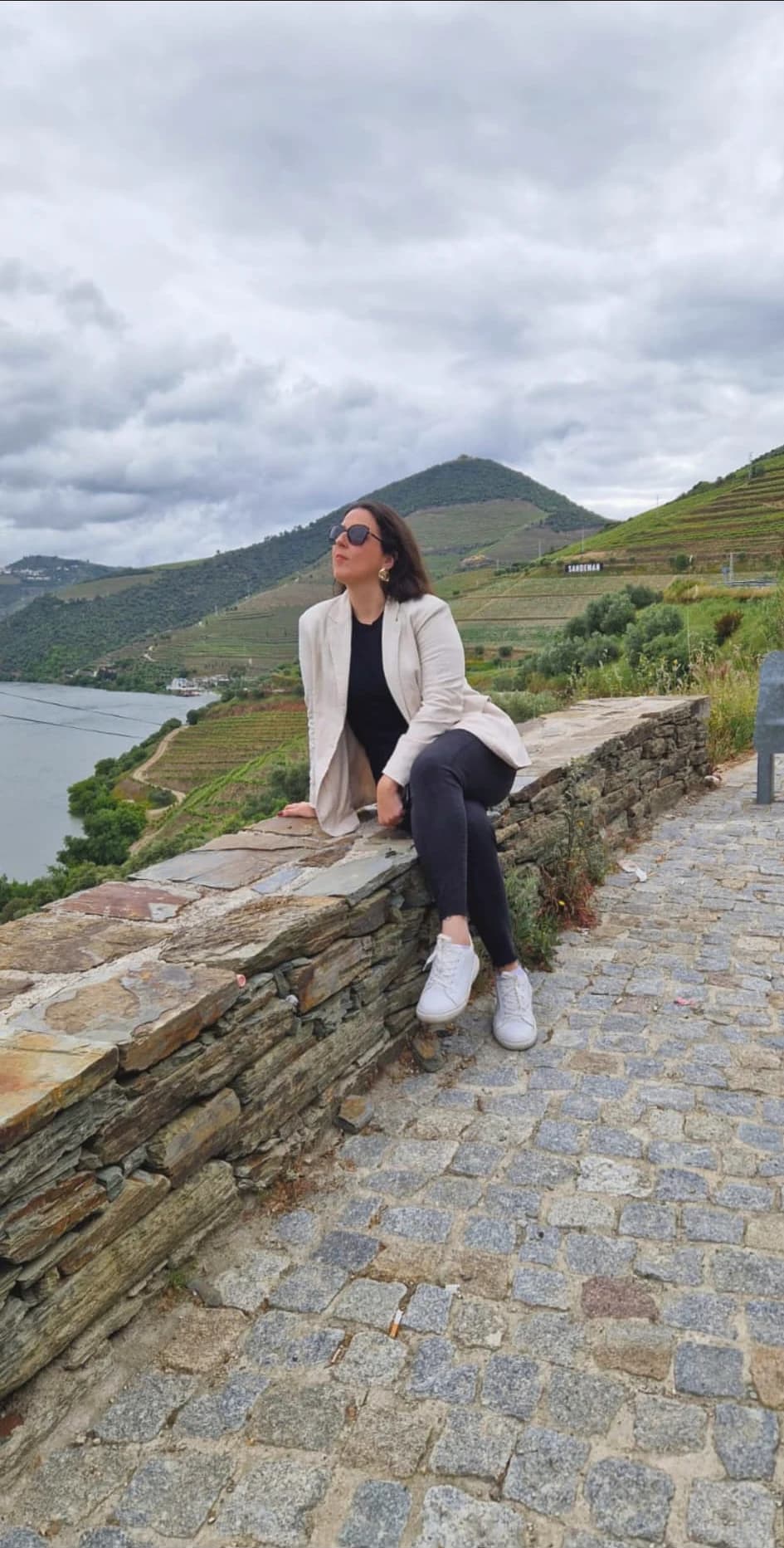 Lívia Belfort sentada em frente aos vinhedos
